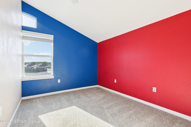 carpeted spare room with baseboards and lofted ceiling