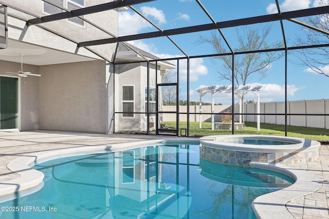 view of swimming pool with a pool with connected hot tub, ceiling fan, fence, glass enclosure, and a patio area