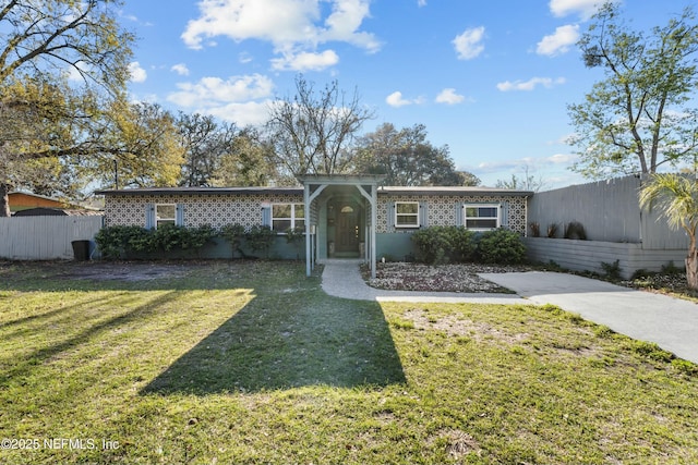 view of front of house with brick siding, a front yard, and fence