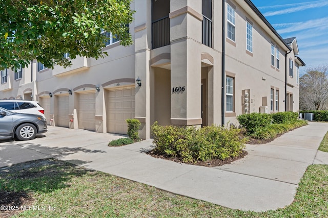 view of property exterior with an attached garage, cooling unit, driveway, and stucco siding