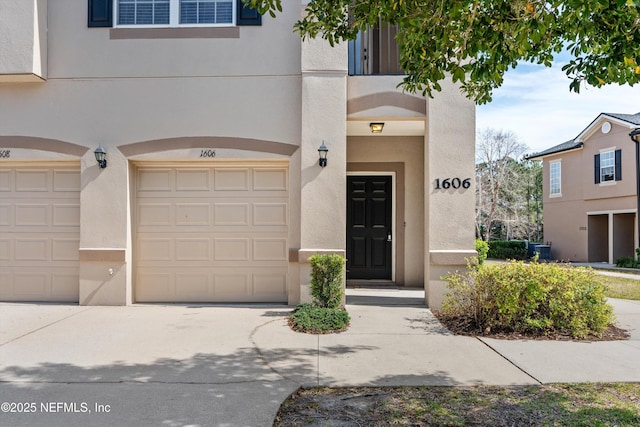 view of front of house featuring cooling unit, a garage, driveway, and stucco siding