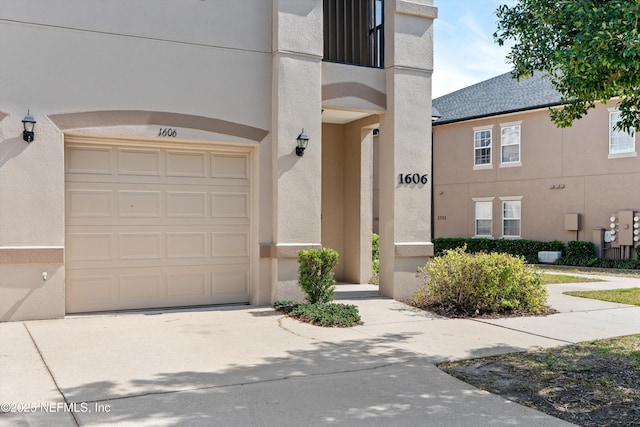 exterior space featuring concrete driveway, a garage, and stucco siding