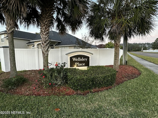 community / neighborhood sign with a lawn and fence