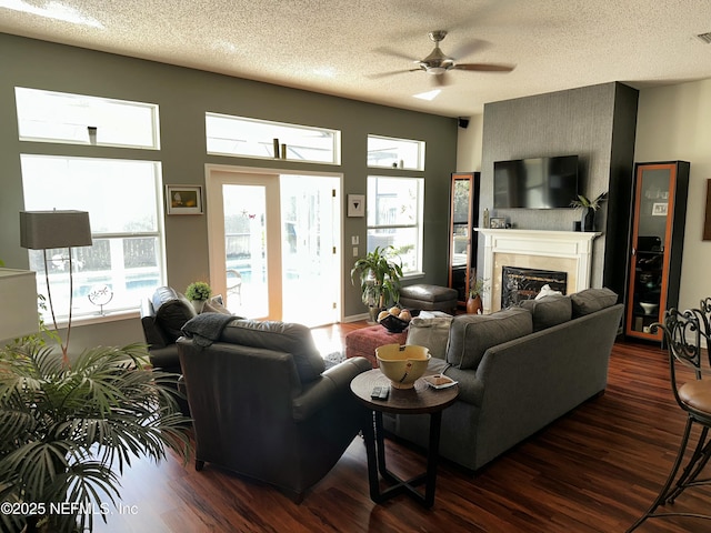 living area with visible vents, dark wood-type flooring, ceiling fan, and a fireplace