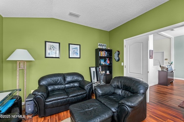 living room featuring visible vents, baseboards, vaulted ceiling, wood finished floors, and a textured ceiling