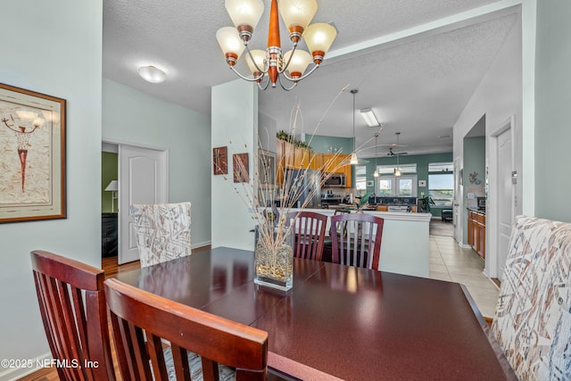 dining space with a textured ceiling, light tile patterned floors, and a chandelier