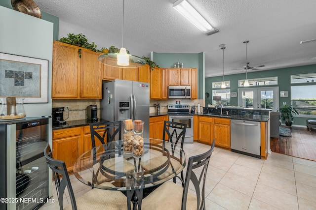 kitchen featuring a ceiling fan, a peninsula, a sink, stainless steel appliances, and wine cooler