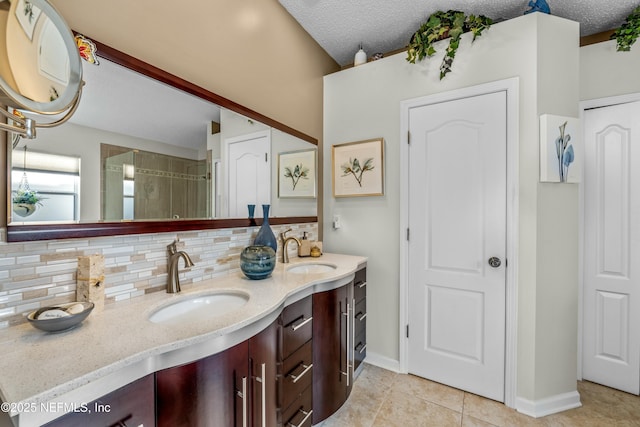 full bath with double vanity, a textured ceiling, tasteful backsplash, and a sink