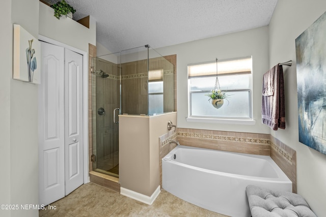 full bathroom with a bath, tile patterned flooring, a stall shower, and a textured ceiling