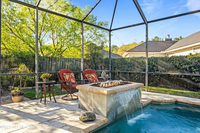 view of pool featuring glass enclosure, a patio, fence, a fenced in pool, and an outdoor fire pit