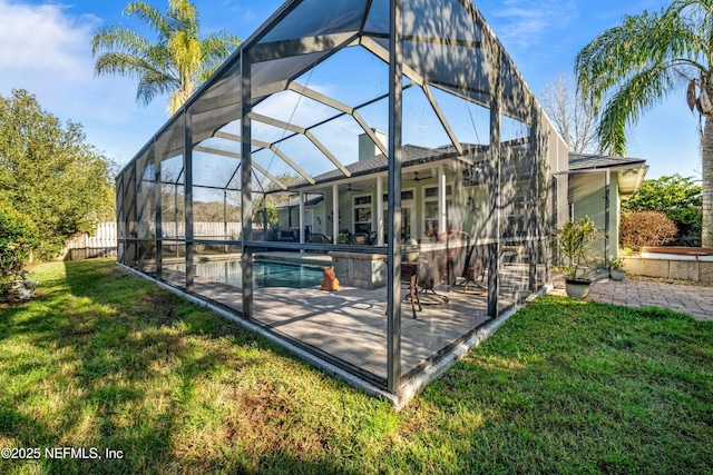 exterior space with glass enclosure, a patio, a lawn, and ceiling fan