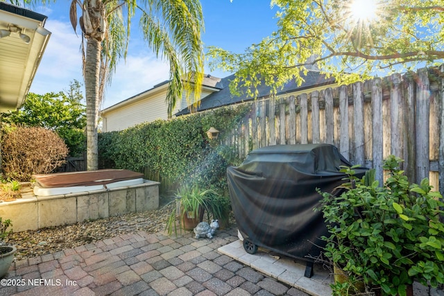 view of patio featuring a grill, a jacuzzi, and a fenced backyard