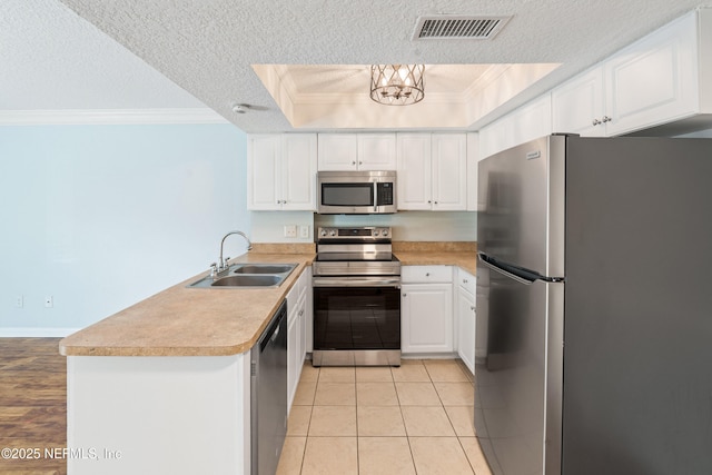 kitchen with visible vents, a sink, stainless steel appliances, a peninsula, and crown molding