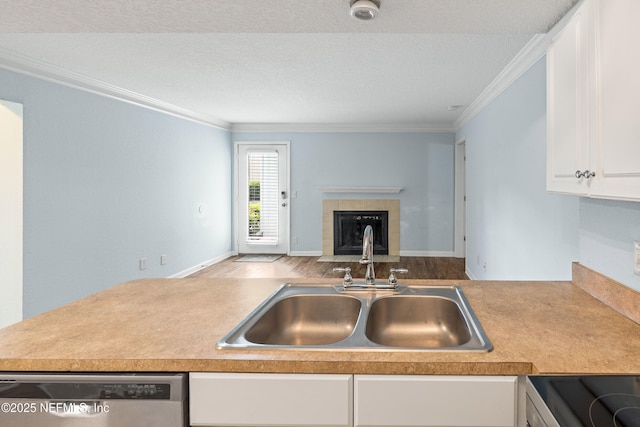 kitchen with a sink, white cabinetry, a fireplace, crown molding, and dishwasher