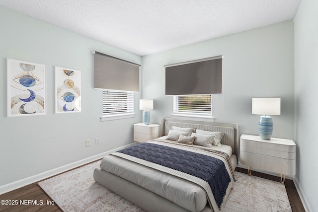 bedroom featuring a textured ceiling, baseboards, and wood finished floors