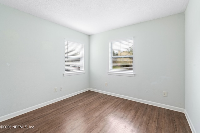 unfurnished room featuring a textured ceiling, dark wood-type flooring, and baseboards