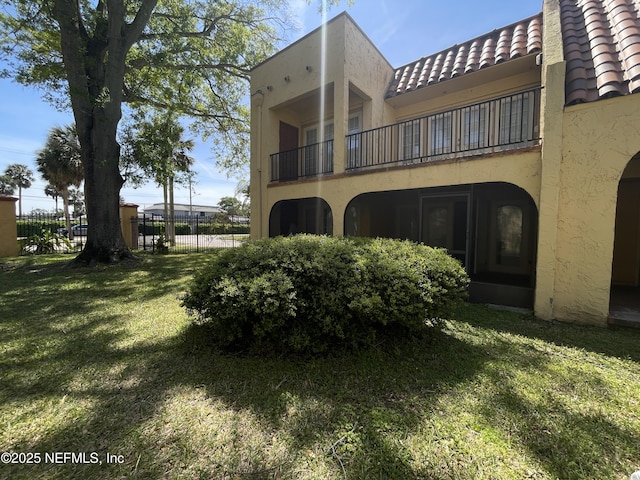 6655 Bell Tower Ct Unit 7, Jacksonville, FL 32217 - back of house with a tile roof, stucco siding, fence, a balcony, and a lawn