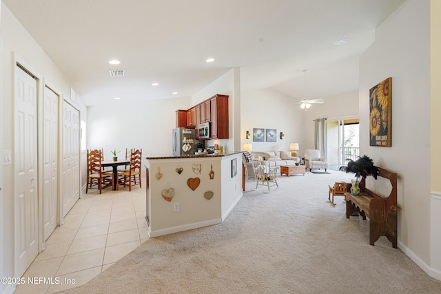 kitchen with stainless steel microwave, light carpet, open floor plan, and freestanding refrigerator