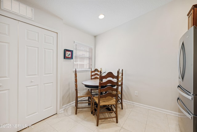 dining area featuring light tile patterned flooring, baseboards, visible vents, and a textured ceiling