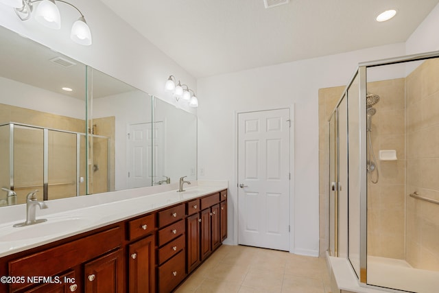 full bath with a sink, double vanity, a shower stall, and tile patterned flooring