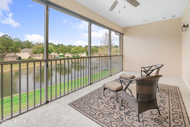 sunroom with a ceiling fan and a water view