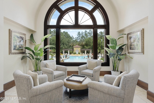 living area featuring a towering ceiling, baseboards, and a wealth of natural light