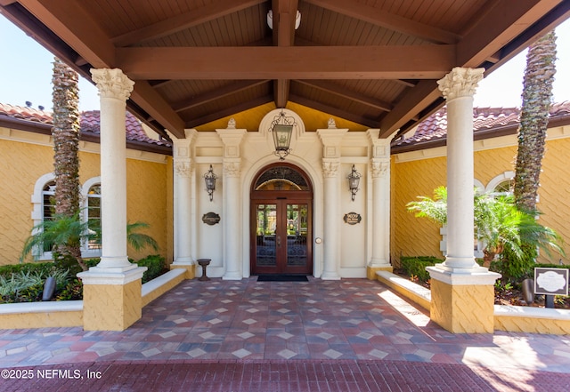 view of exterior entry featuring stucco siding, french doors, and a tile roof