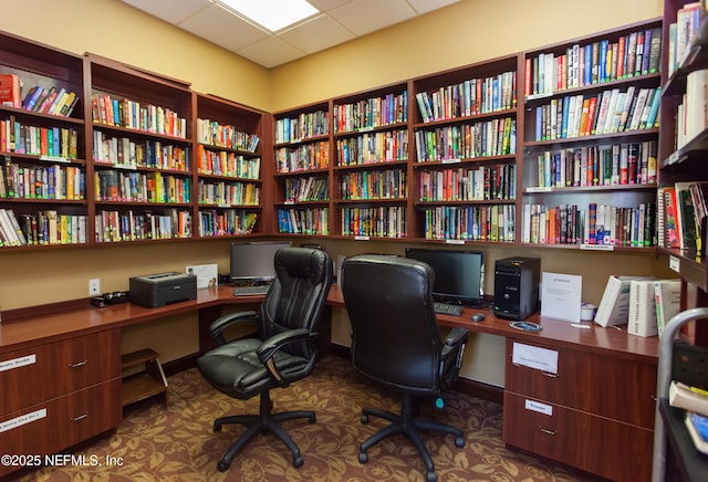 home office with a drop ceiling and bookshelves