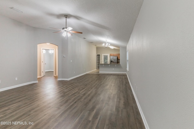 unfurnished living room featuring dark wood-style floors, lofted ceiling, arched walkways, a textured ceiling, and ceiling fan with notable chandelier