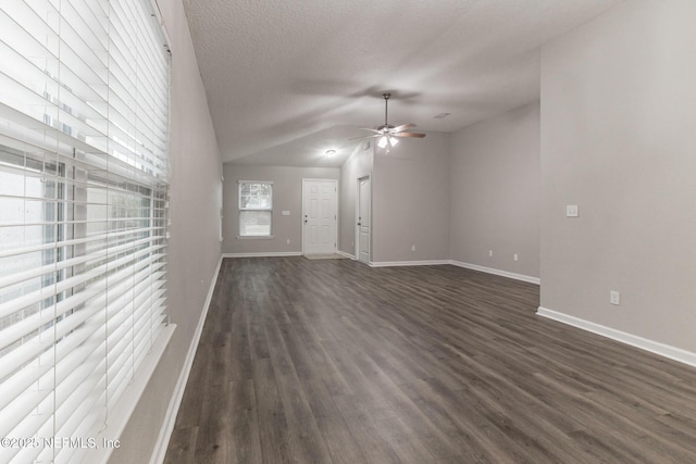 unfurnished living room with a ceiling fan, baseboards, dark wood-type flooring, vaulted ceiling, and a textured ceiling