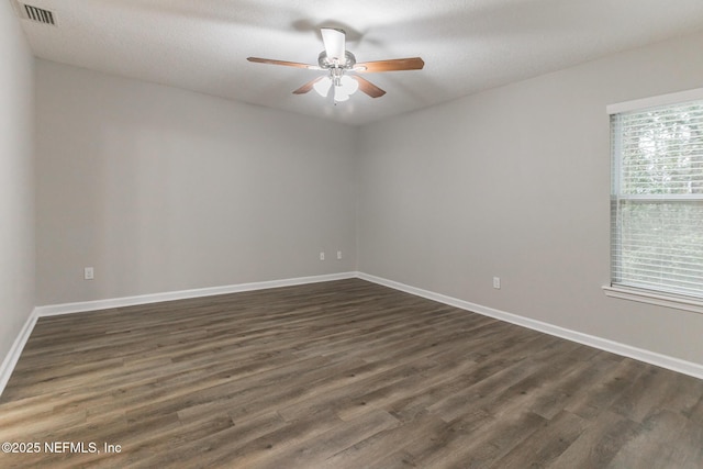 spare room with visible vents, baseboards, ceiling fan, and dark wood-style flooring