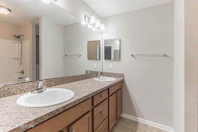 bathroom featuring tile patterned flooring, double vanity, baseboards, and a sink