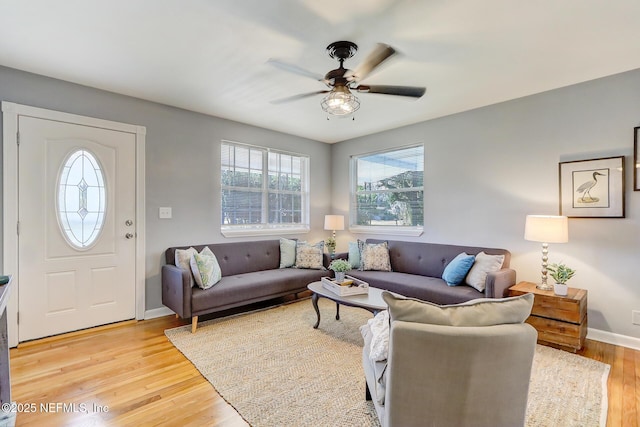 living room featuring baseboards, light wood-type flooring, and ceiling fan