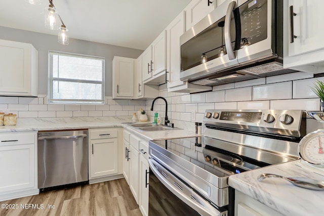 kitchen with decorative backsplash, white cabinets, and stainless steel appliances