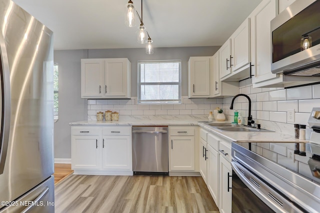 kitchen featuring decorative backsplash, white cabinetry, stainless steel appliances, and a sink