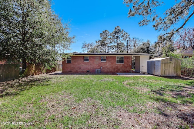 rear view of house featuring a patio, fence, a storage unit, crawl space, and brick siding