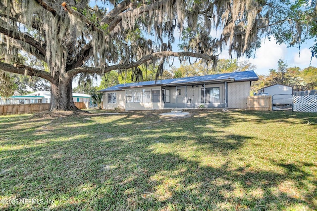 back of house featuring a yard, fence, and brick siding