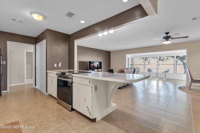 kitchen featuring visible vents, a peninsula, white cabinets, light countertops, and stainless steel electric range oven