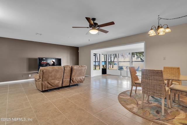 living room featuring light tile patterned floors, visible vents, baseboards, and ceiling fan with notable chandelier