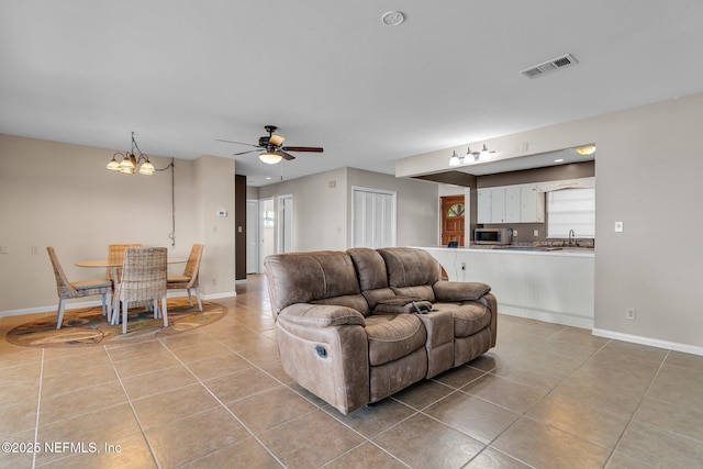 living room with baseboards, visible vents, light tile patterned flooring, ceiling fan with notable chandelier, and a wealth of natural light