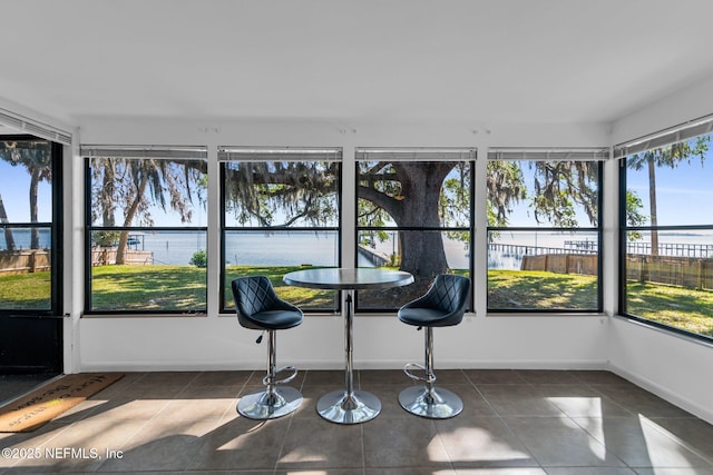 sunroom featuring a water view