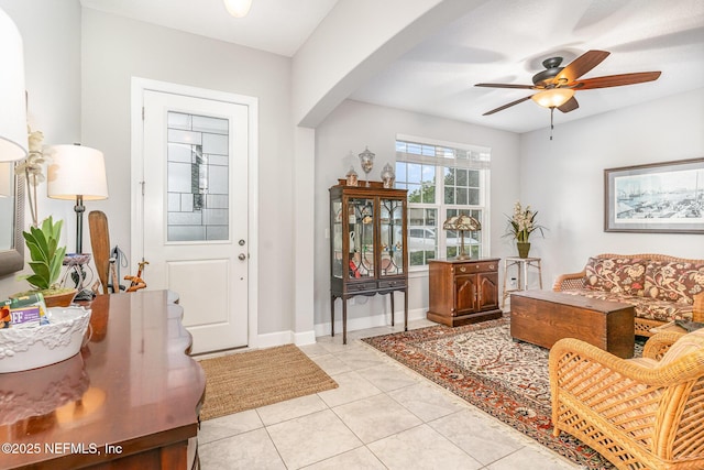 entrance foyer featuring light tile patterned flooring, ceiling fan, baseboards, and arched walkways