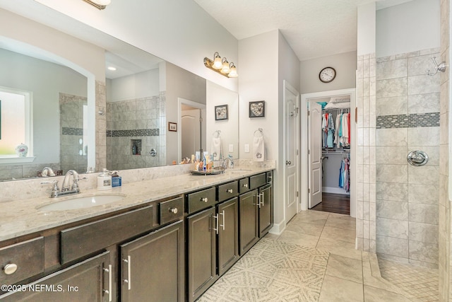 bathroom with tile patterned floors, a walk in shower, double vanity, and a sink