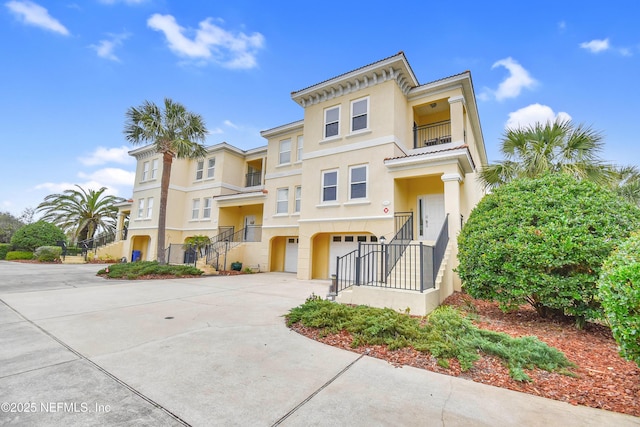 view of front of home with a balcony, stucco siding, driveway, and a garage