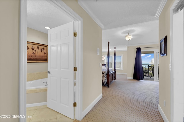 hallway with a textured ceiling, crown molding, and baseboards