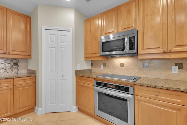 kitchen featuring decorative backsplash, light stone counters, light tile patterned floors, and stainless steel appliances