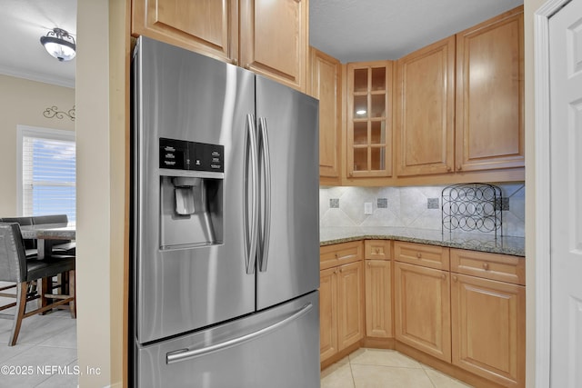 kitchen featuring stainless steel fridge, crown molding, light tile patterned floors, glass insert cabinets, and light stone countertops