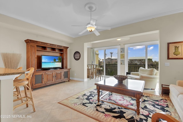 living room featuring light tile patterned floors, baseboards, ornamental molding, and a ceiling fan