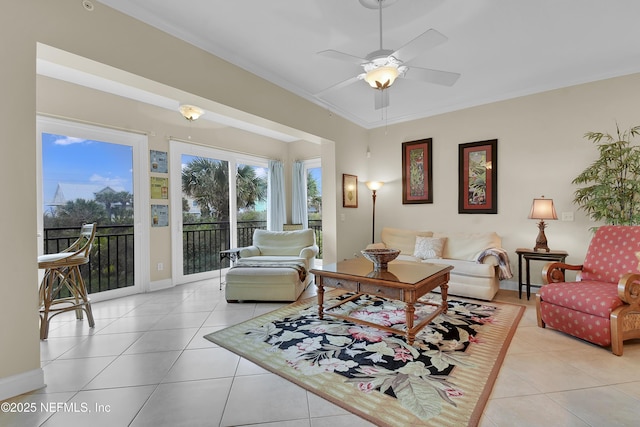 living area with crown molding, light tile patterned floors, a ceiling fan, and baseboards