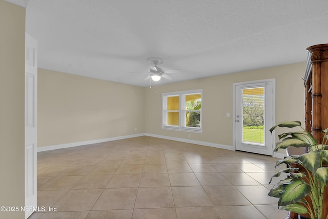 empty room featuring light tile patterned floors, ceiling fan, a textured ceiling, and baseboards